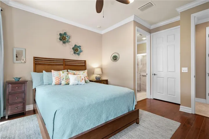 Spacious room featuring rich wood-finish flooring, crown molding, and a ceiling fan