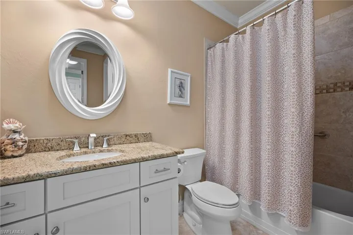 Bathroom featuring a white vanity with a granite-finish countertop, undermount sink, and chrome faucet