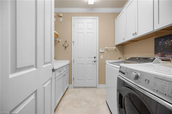 Laundry room featuring white cabinetry, a utility sink, and tile flooring