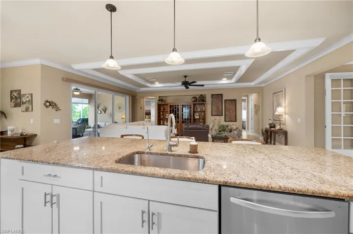 Kitchen island featuring a stainless steel sink, light-toned countertop, and white cabinetry