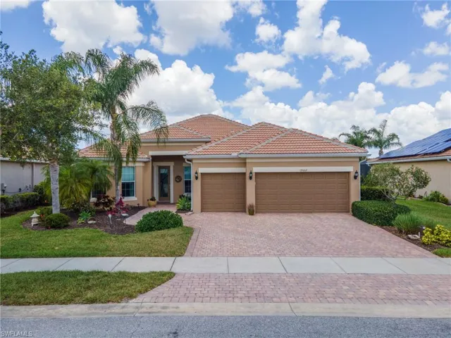 Stucco exterior with a terracotta tile roof, paver driveway, and a two-car garage