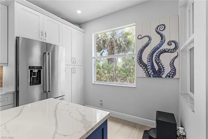 Featuring high end fridge, baseboards, light wood-type flooring, recessed lighting, and a closet