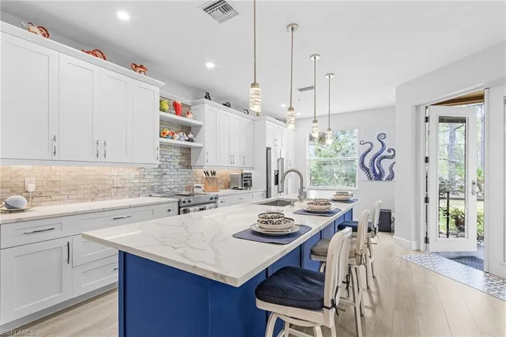 Kitchen with a sink, premium appliances, decorative backsplash, open shelves, and light wood finished floors