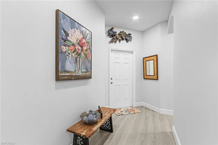 Hallway with light wood-type flooring, baseboards, and recessed lighting