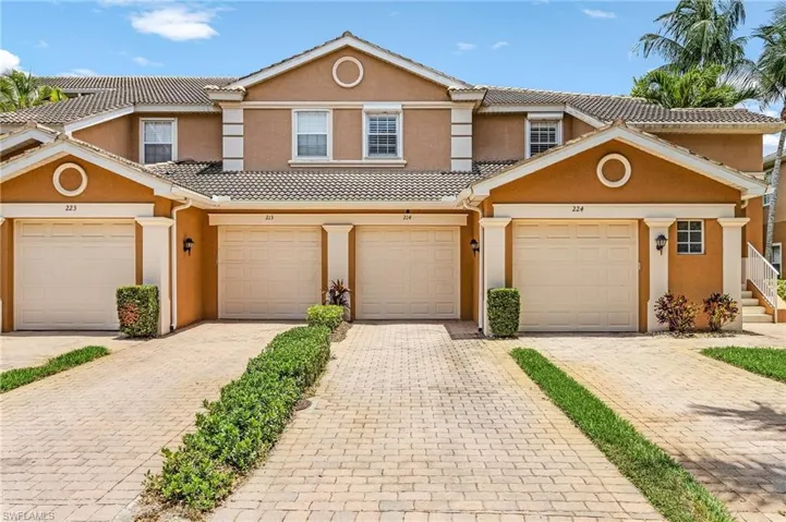 View of property featuring stucco siding, a tile roof, and decorative driveway