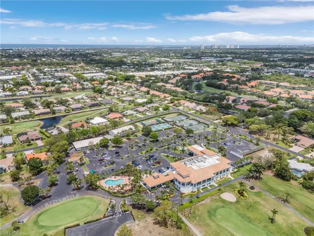 Aerial view of property and surrounding area featuring a local golf course, a large body of water, and nearby suburban area