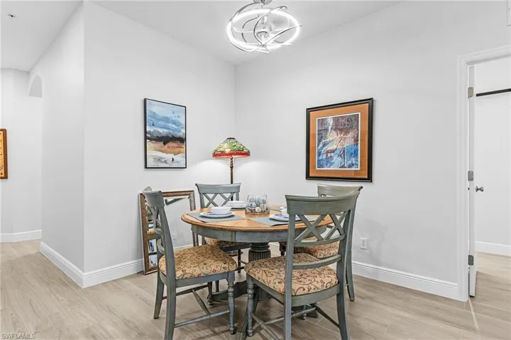 Dining area featuring light wood-style flooring, arched walkways, a chandelier, and baseboards