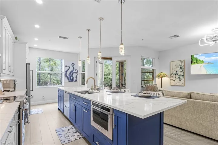 Kitchen with a sink, blue cabinets, appliances with stainless steel finishes, white cabinetry, and open floor plan
