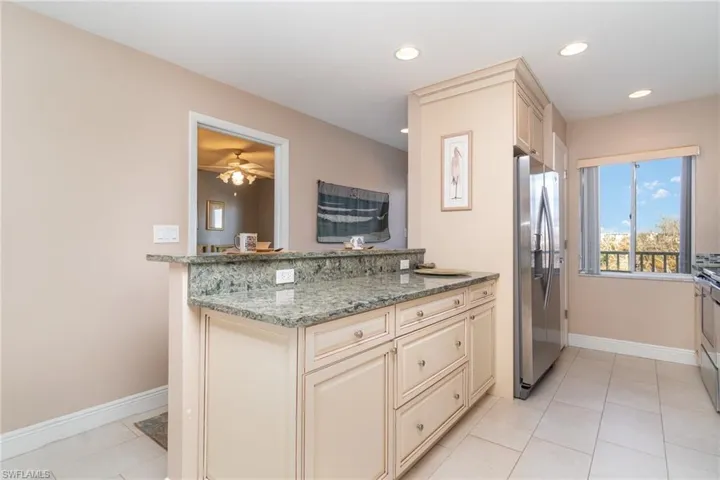 Kitchen with light stone countertops, appliances with stainless steel finishes,  light tile patterned floors, and cream cabinets