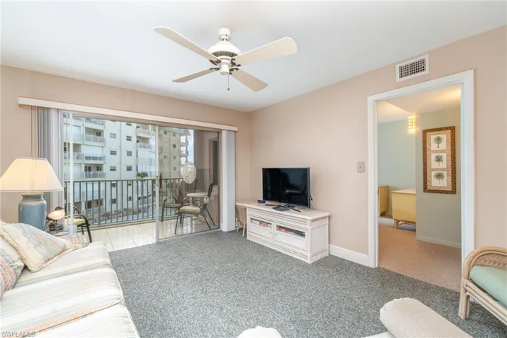 Dining room featuring light tile patterned flooring and ceiling fan with notable chandelierCarpeted living room featuring ceiling fan with mirrored wall offering reflection view of the Gulf Of Mexico