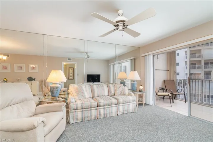 Dining room featuring light tile patterned flooring and ceiling fan with notable chandelierCarpeted living room featuring ceiling fan with mirrored wall offering reflection view of the Gulf Of Mexico