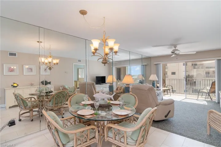 Dining room featuring light tile patterned flooring and ceiling fan with notable chandelierCarpeted living room featuring ceiling fan with mirrored wall offering reflection view of the Gulf Of Mexico