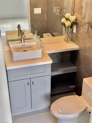 Bathroom with vanity, toilet, tile patterned floors, and tile walls