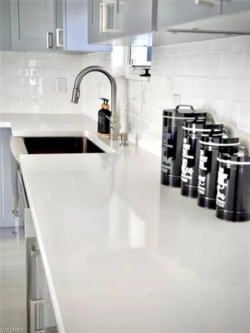 Interior details featuring gray cabinets, tasteful backsplash, and sink