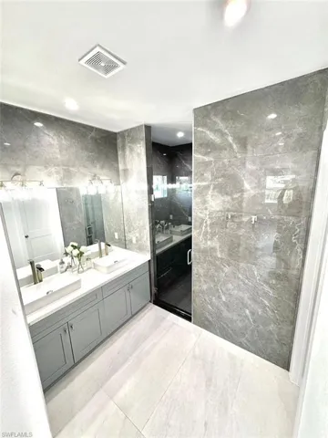 Bathroom featuring vanity, walk in shower, and tile walls