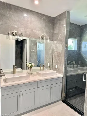 Bathroom with vanity, an enclosed shower, and tile walls