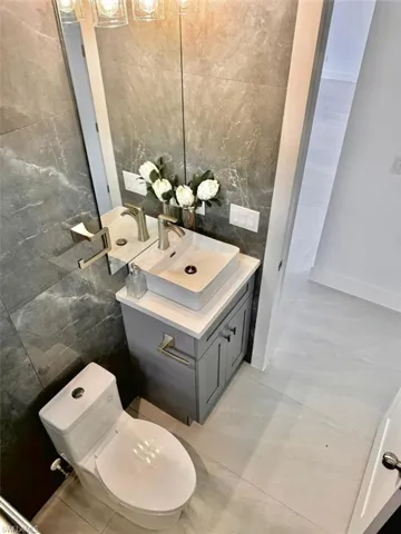Bathroom with vanity, toilet, and tile walls