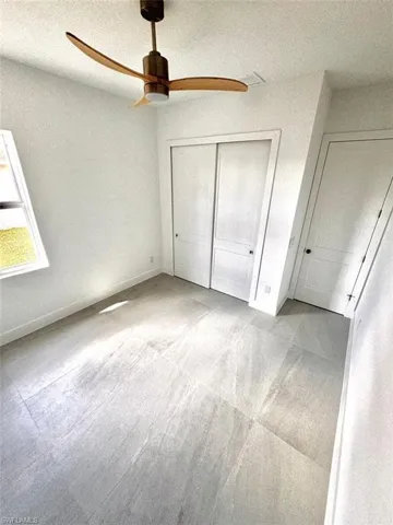 Unfurnished bedroom featuring a textured ceiling, a closet, and ceiling fan