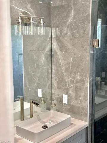 Bathroom featuring vanity, tile walls, and decorative backsplash