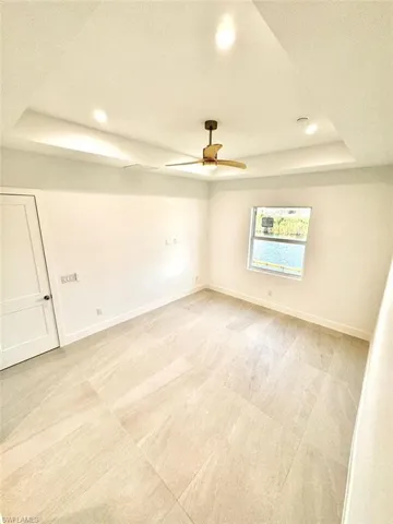 Spare room featuring ceiling fan, a textured ceiling, and a tray ceiling