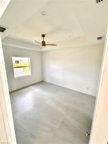 Unfurnished room featuring a textured ceiling, a raised ceiling, and ceiling fan