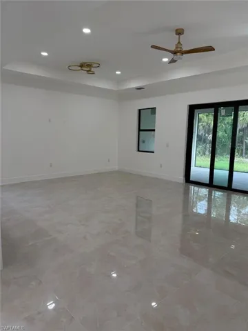 Empty room with recessed lighting, a raised ceiling, and ceiling fan