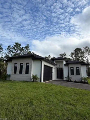 Prairie-style house with asphalt driveway, a front lawn, and a garage