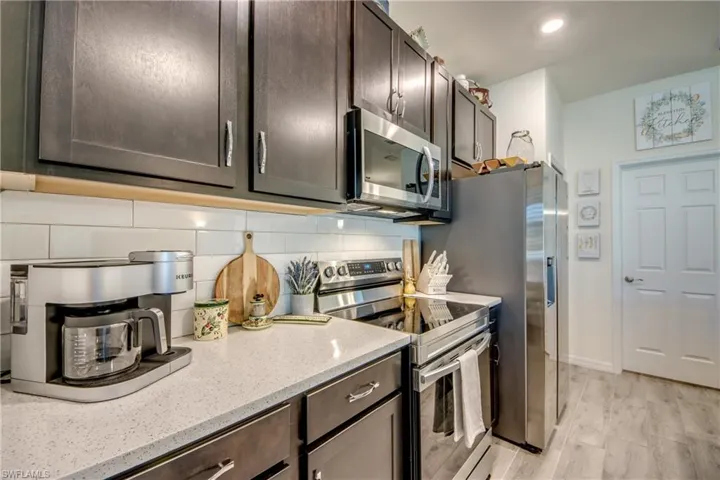 Fabulous quartz counter and subway tile backsplash accent the dark wood cabinets. The laundry room (and garage beyond) is through the closed door on the right.