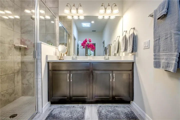Double vanity, tiled shower, and separate water closet are features in the ensuite primary bathroom. Skylight was installed to provide light without having to flip a switch. Nightlight on skylight is additional feature.