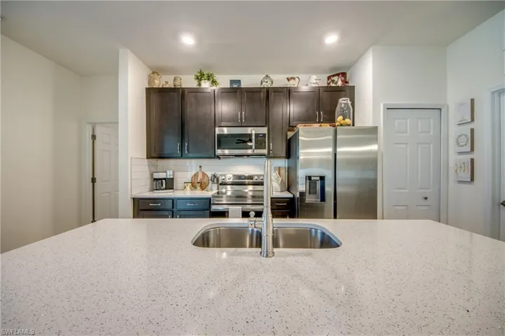 Gorgeous quartz counters adorn the kitchen and both bathrooms. There is a pantry to the right of the refrigerator. The nearby laundry room also has room for storage.