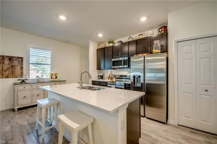 Beautiful white quartz countertops and dark cabinetry adorn this kitchen. Added features include the breakfast bar, stainless steel appliances, and a pantry.