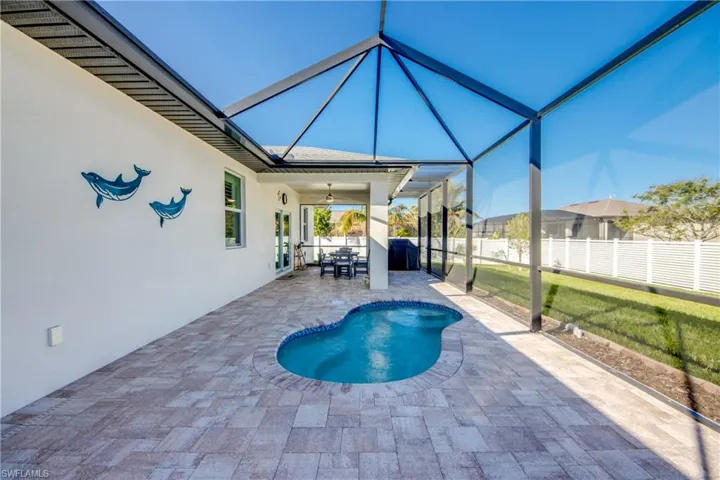 Screened lanai is partially covered and features a 2024 built spool (spa/pool) with pebble finish and 8 jets. Enjoy a relaxing spa experience in your backyard.