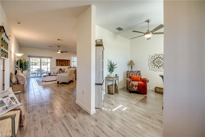 View from the foyer shows the den/office on the right and the Great Room down the hallway. Plank tile flooring is throughout the home.