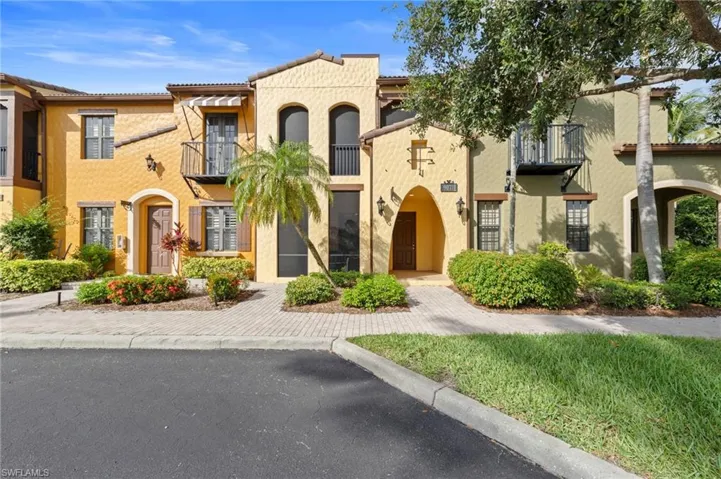 Mediterranean-style condos with stucco exterior, arched entryways, and decorative iron balconies. NEW FRONT DOOR TOUCH KEYPAD (2026), NEW NO-SEE-UM SCREEN LANAI (2025), NEW ROOF (2024), NEW AIR CONDITIONER (2021), NEW INTERIOR PAINT THROUGHOUT (2018)