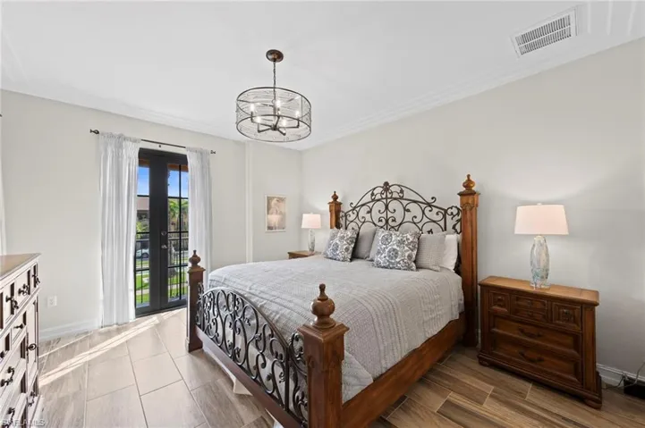 Primary bedroom featuring French doors, wood-finish tile flooring, crown molding, and a drum chandelier. NEW TILE FLOOR (2018)