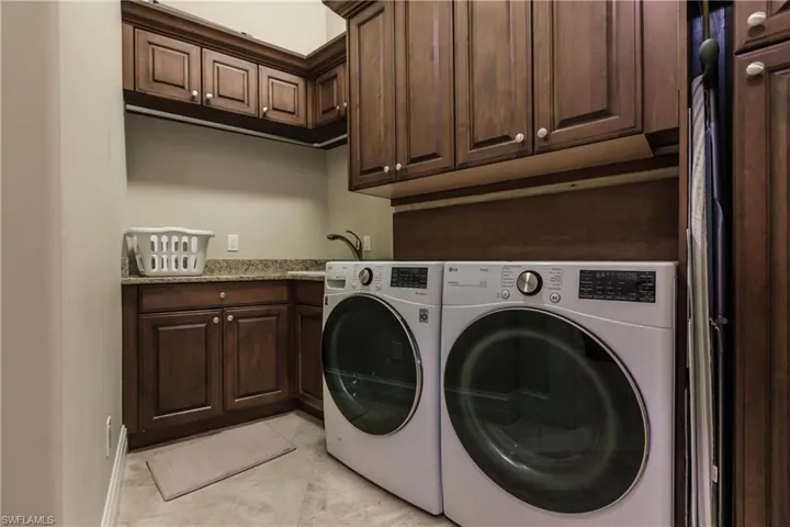 Clothes washing area with cabinets, washer and dryer, and sink
