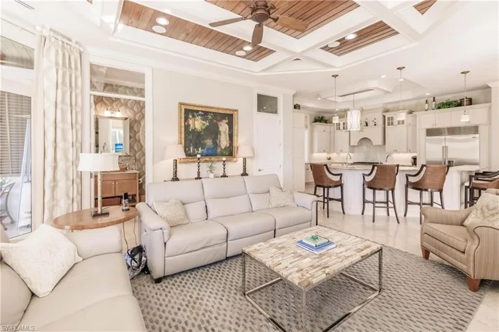 Living room with crown molding, ceiling fan, coffered ceiling, and beamed ceiling
