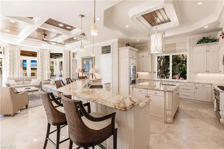 Kitchen featuring sink, a breakfast bar area, a spacious island, light stone countertops, and decorative light fixtures