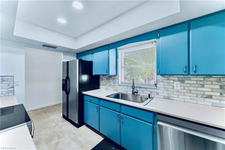 Kitchen featuring blue cabinetry, light countertops, stainless steel appliances, backsplash, and recessed lighting