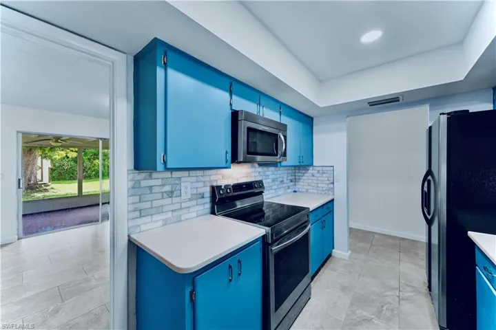 Kitchen with blue cabinets, stainless steel appliances, tasteful backsplash, and a tray ceiling