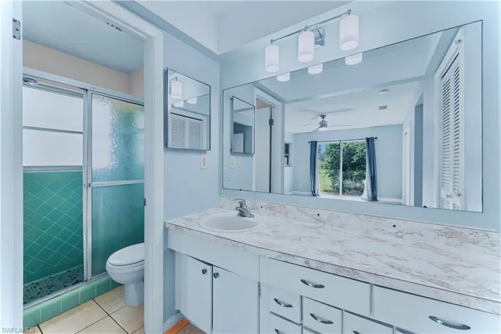 Bathroom with a shower stall, vanity, light tile patterned floors, and a closet
