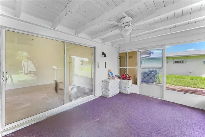 Unfurnished sunroom with beam ceiling and a ceiling fan