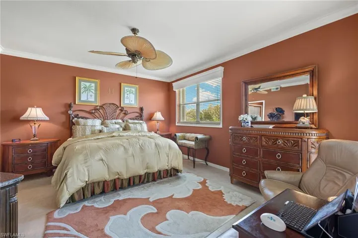 Bedroom with ceiling fan, crown molding, and light colored carpet