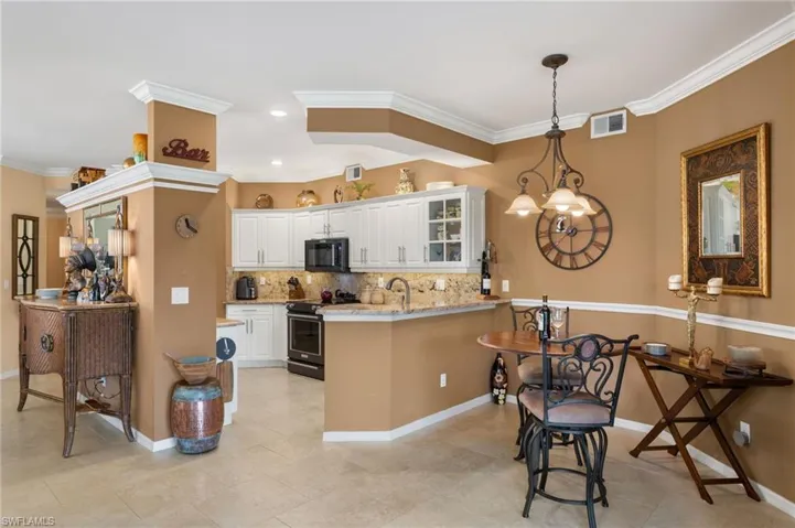 Kitchen with light stone counters, white cabinets, kitchen peninsula, crown molding, and stainless steel electric stove