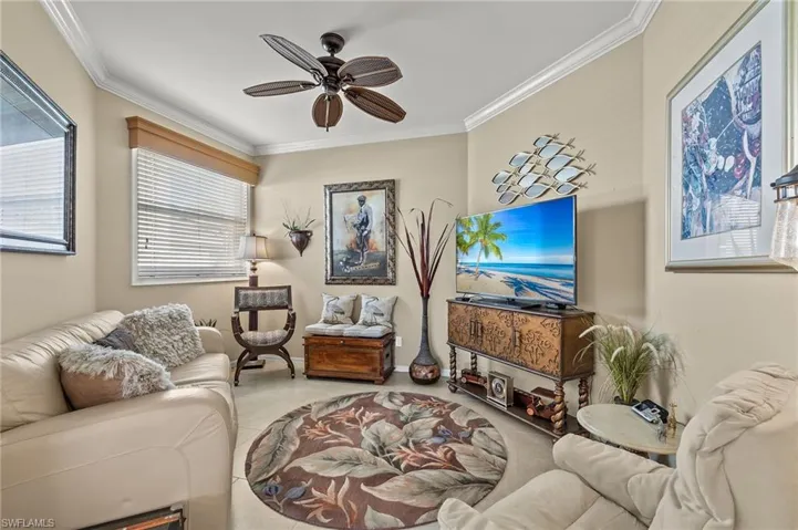 Carpeted living room featuring ceiling fan and crown molding