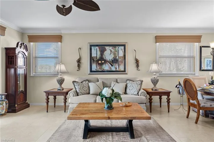 Living room featuring ceiling fan, light tile patterned floors, and ornamental molding