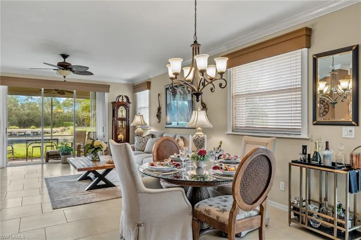 Tiled dining space featuring ornamental molding and ceiling fan with notable chandelier