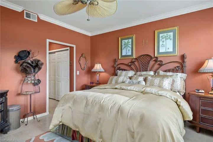 Bedroom with a closet, ceiling fan, crown molding, and light tile patterned floors