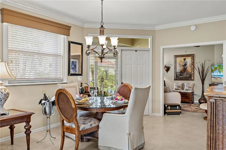 Tiled dining space featuring a chandelier and crown molding