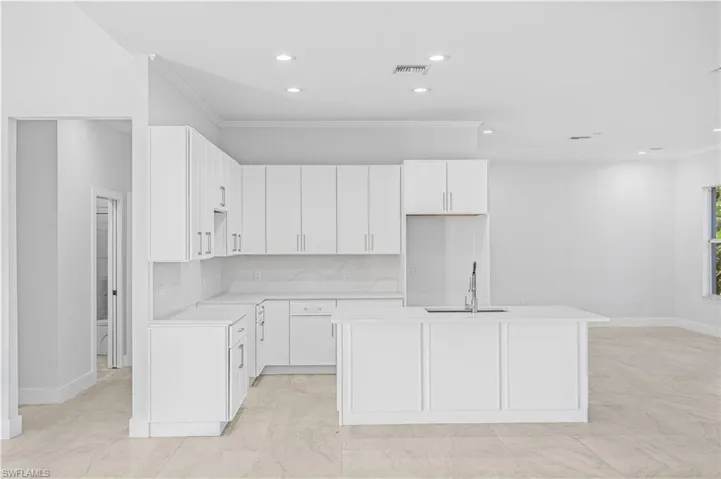 Kitchen featuring crown molding, white cabinets, backsplash, light stone countertops, and recessed lighting